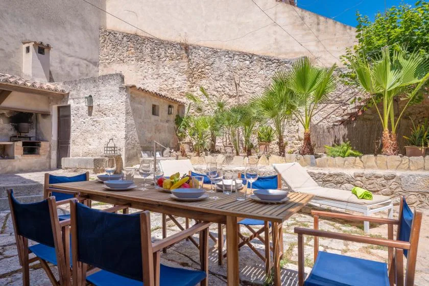 Un patio comedor al aire libre con una mesa puesta y palmeras.