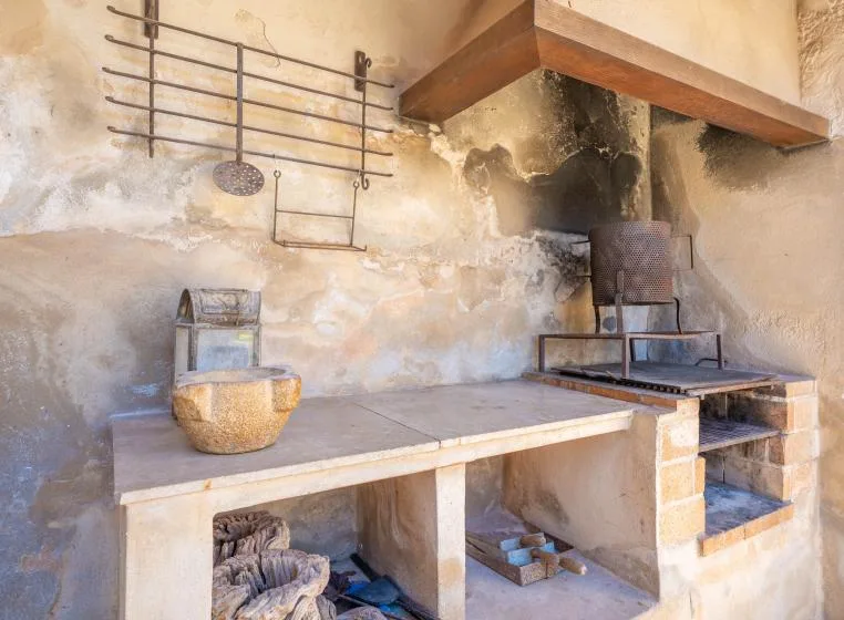 Una cocina rústica con una encimera de piedra y una zona de cocción bajo una gran campana.