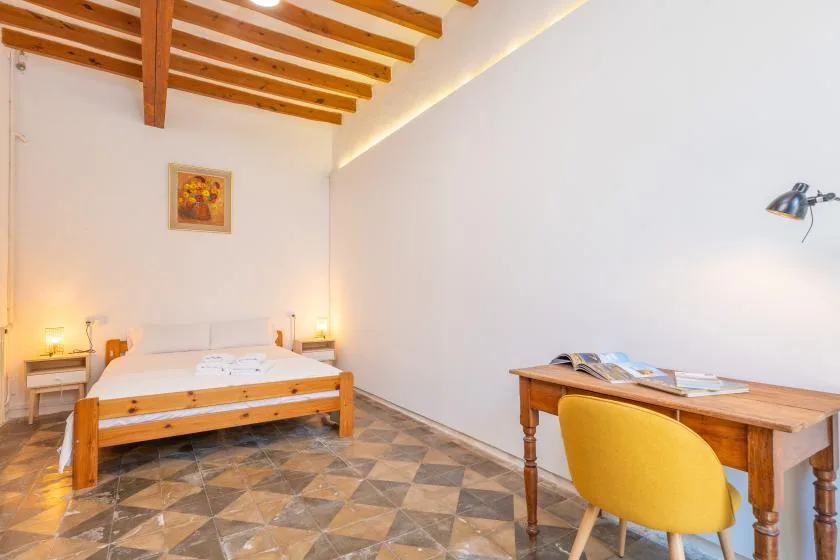 Un dormitorio con una cama y un escritorio de madera bajo vigas expuestas.