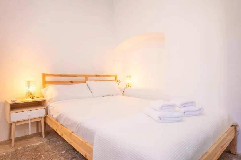 Un dormitorio luminoso con una cama de madera y toallas dobladas.
