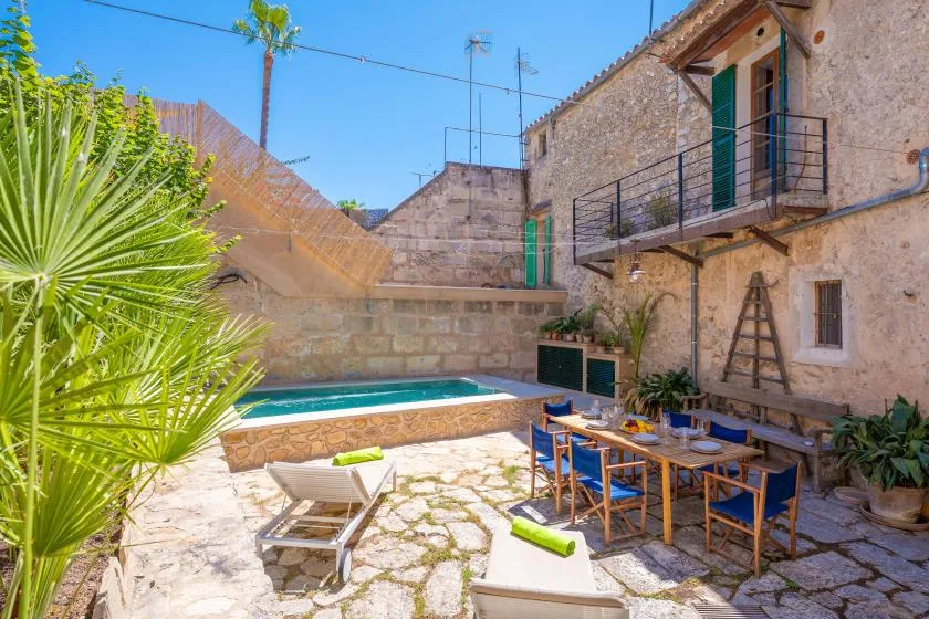 Un patio de piedra con una mesa de comedor junto a una pequeña piscina.