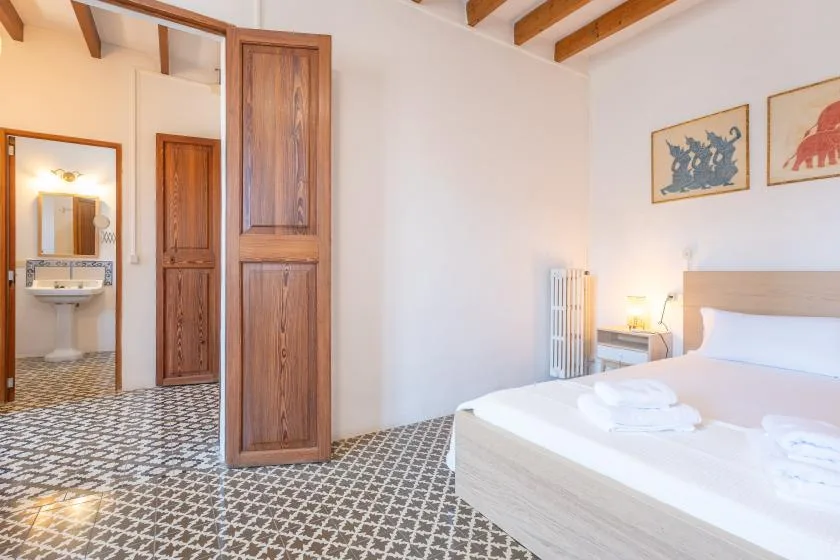 Un dormitorio con una cama, suelo estampado y puertas de madera.
