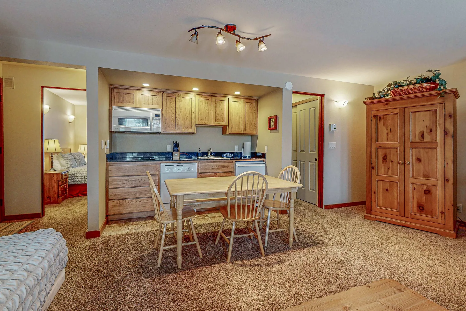 Cocina y comedor con armarios de madera y una mesa.