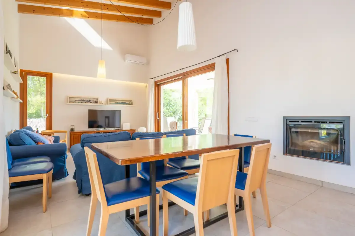 Un luminoso salón-comedor con asientos azules y una mesa de comedor de madera.