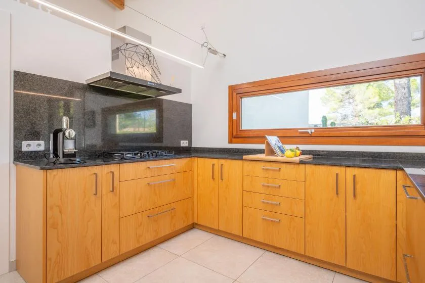 Una cocina luminosa con armarios de madera y una ventana horizontal alargada.