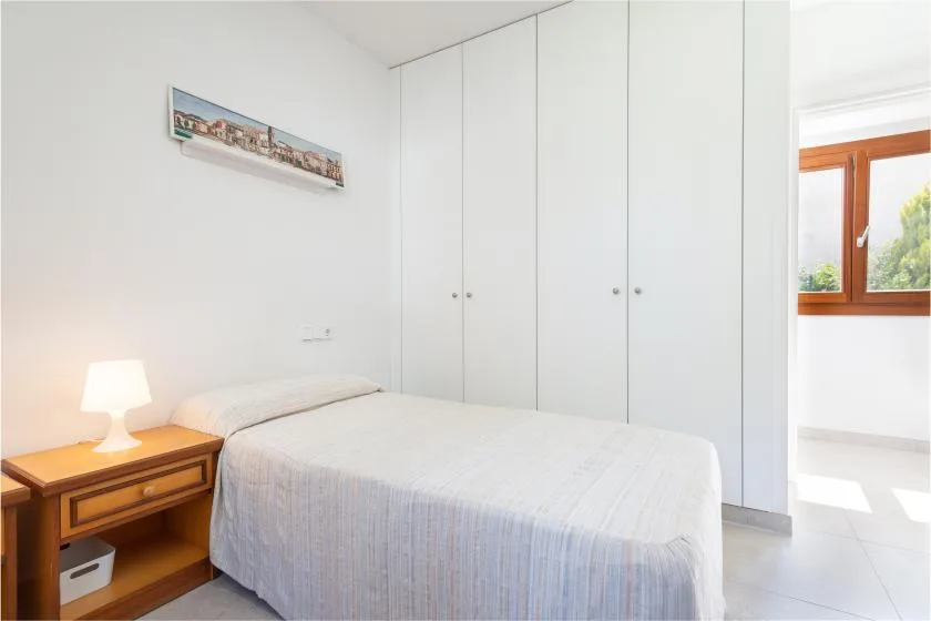Un dormitorio luminoso con cama, mesita de noche y armarios empotrados.