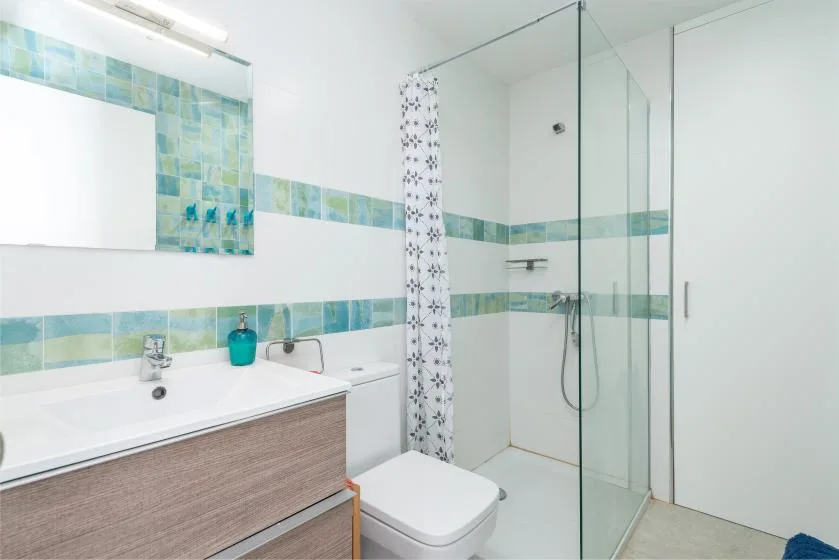Un baño luminoso con lavabo y ducha de cristal.