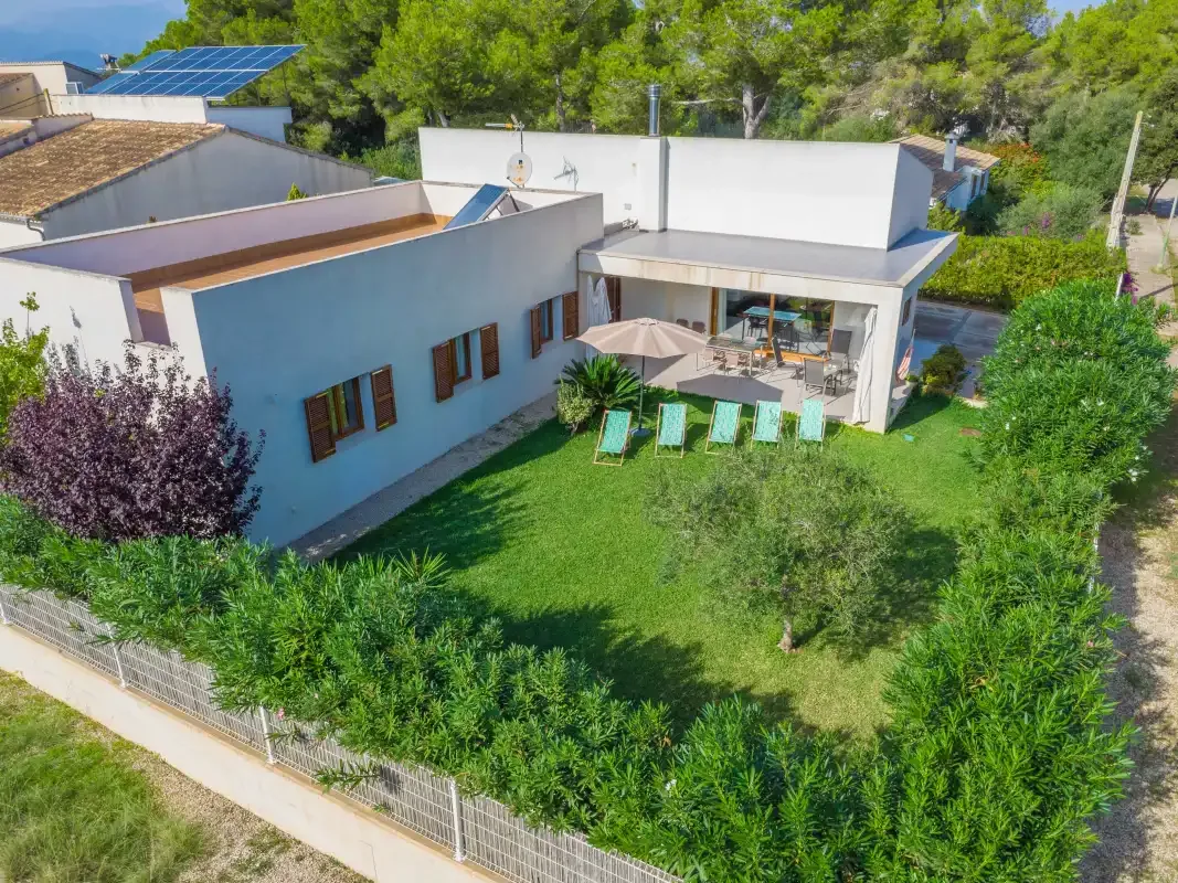 Vista aérea de una casa moderna con césped, patio y asientos al aire libre.