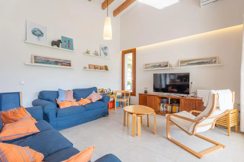 Una sala luminosa con asientos azules, un televisor y una mesa de centro de madera.
