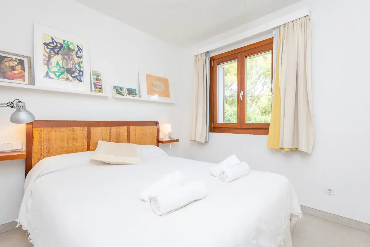 Un dormitorio luminoso con ropa de cama blanca y un cabecero de madera.