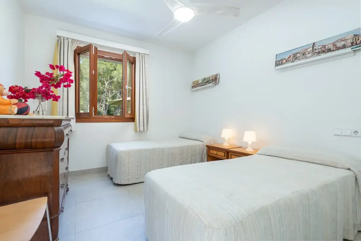 Un dormitorio con dos camas, una ventana y lámparas de noche.