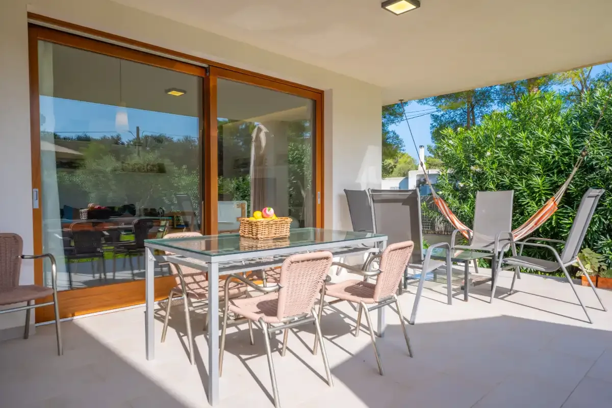 Un comedor en el patio con una mesa y sillas junto a puertas de cristal.