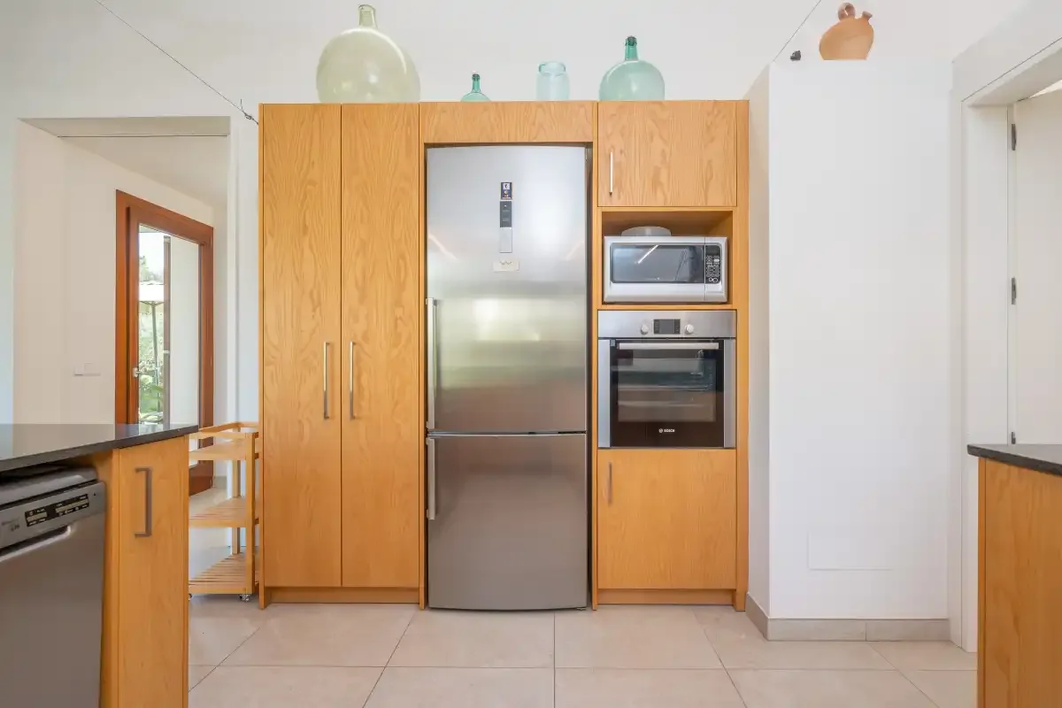 Una cocina luminosa con armarios de madera y un refrigerador de acero inoxidable.
