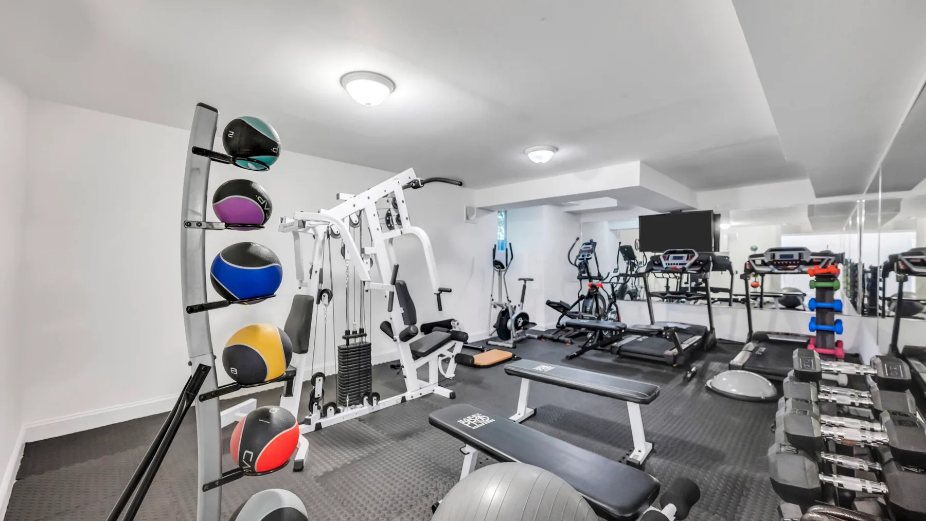 A home gym with weight machines, exercise bikes, and treadmills.
