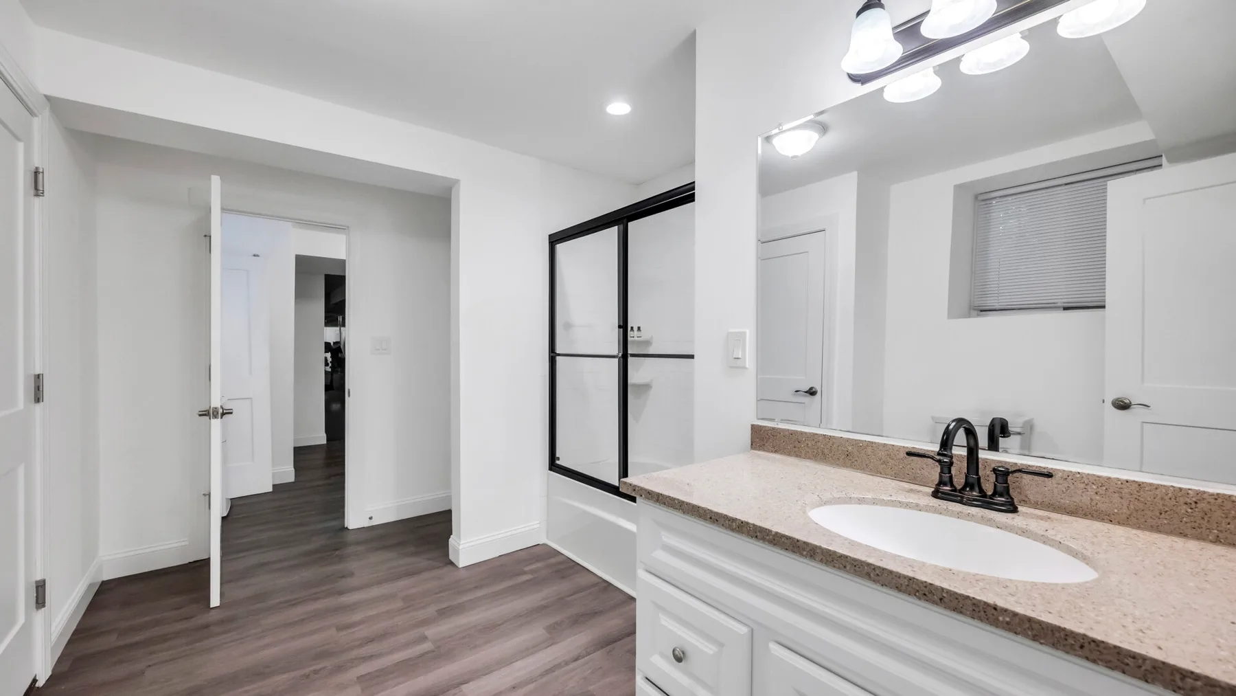 A bathroom vanity with a wide countertop and a large mirror beside an open doorway.