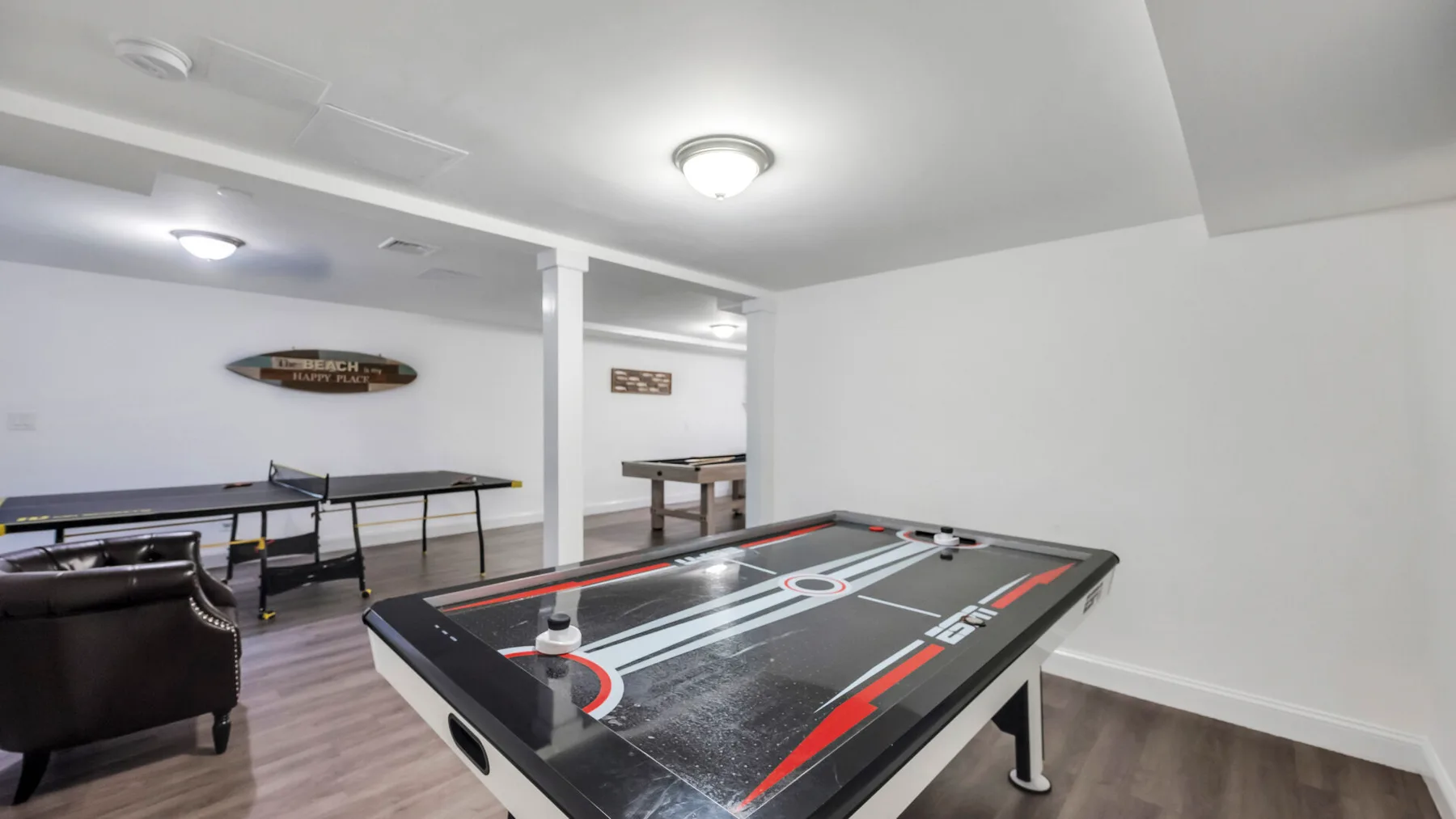A recreation room features an air hockey table and a pool table.