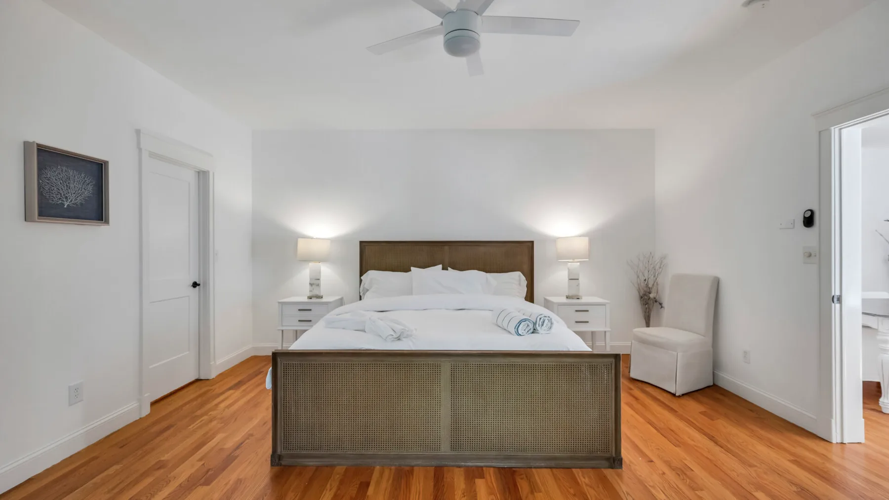 A bright bedroom with a neatly made bed and white bedside tables.