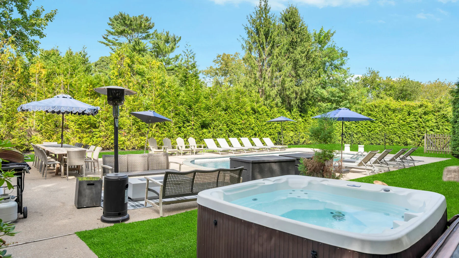 An outdoor pool area with a bubbling hot tub and lounge seating.