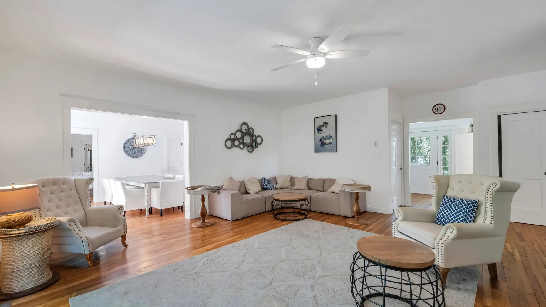 A living room with seating around a coffee table and a ceiling fan overhead.