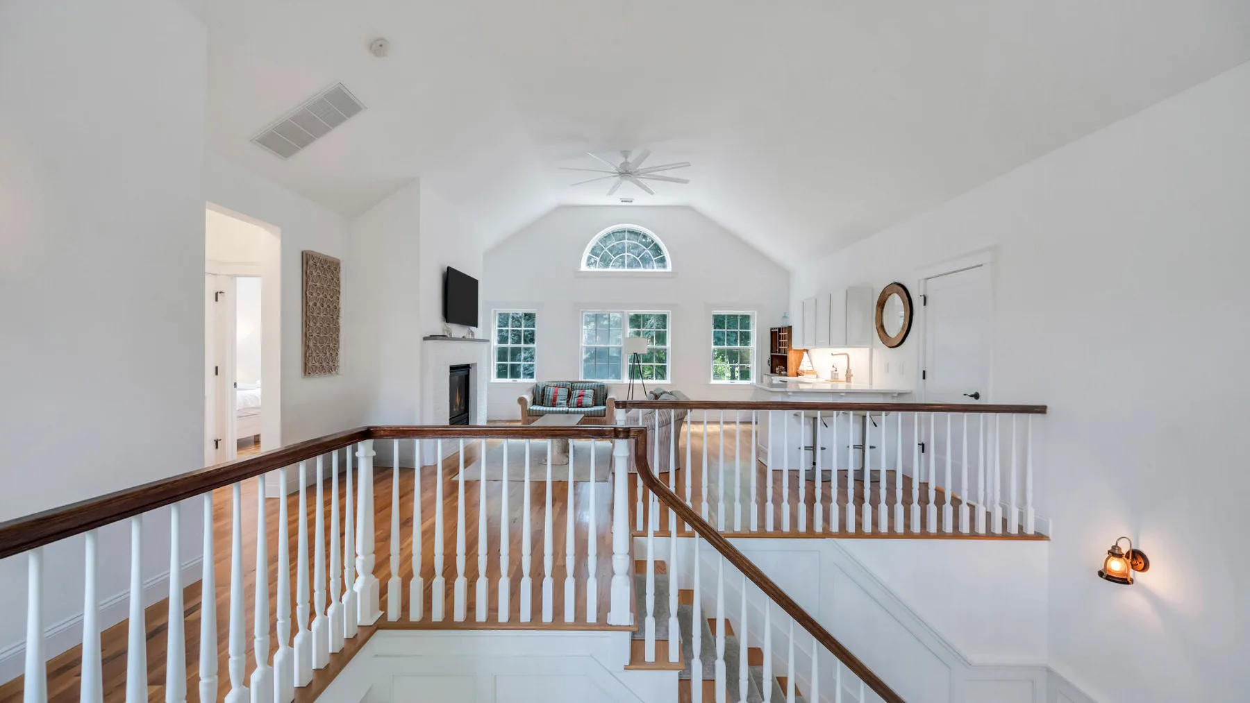 A bright upstairs landing overlooks the living area, with a staircase and white railings.