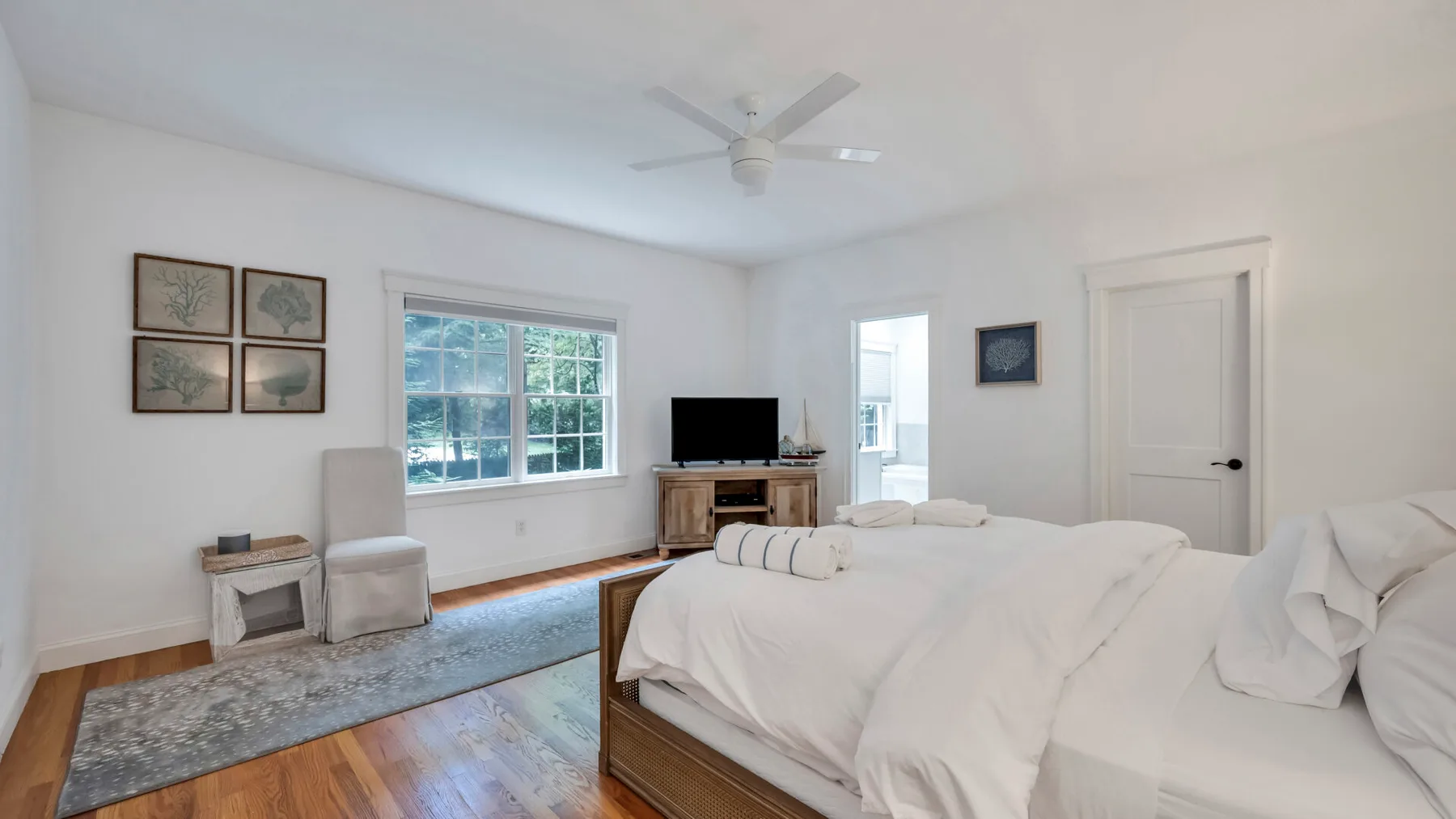 A bright bedroom with a large bed, a window, and a television.