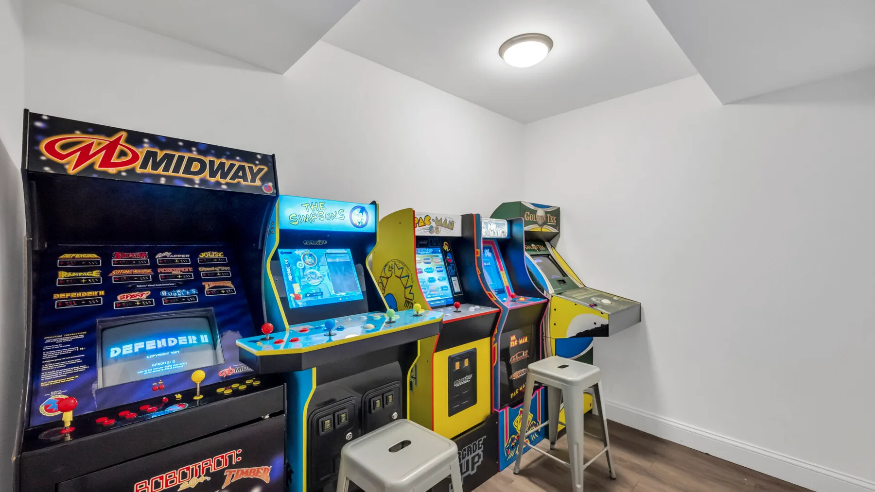 An arcade corner with several colorful video game cabinets and stools.