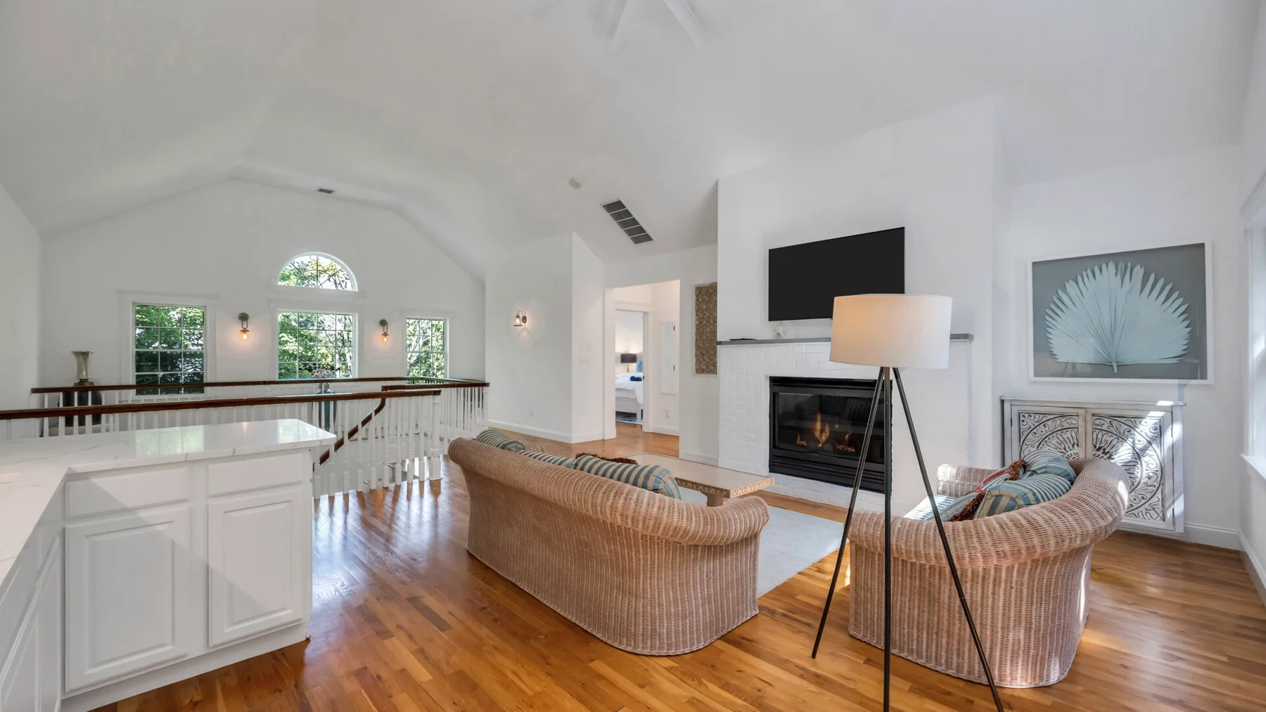 A bright living room with curved seating, a fireplace, and a television.