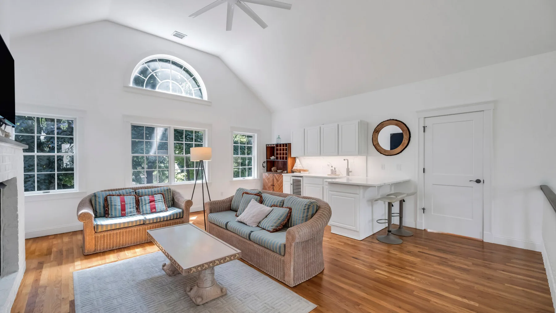 A bright living room with seating, a coffee table, and large windows.