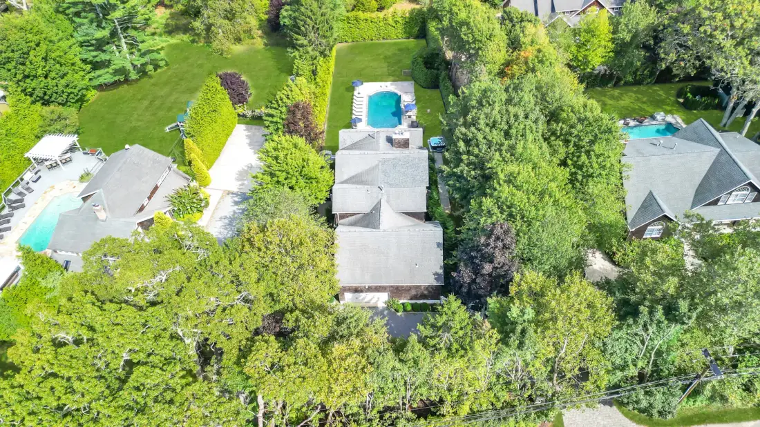 Aerial view of a landscaped property with several buildings and swimming pools.