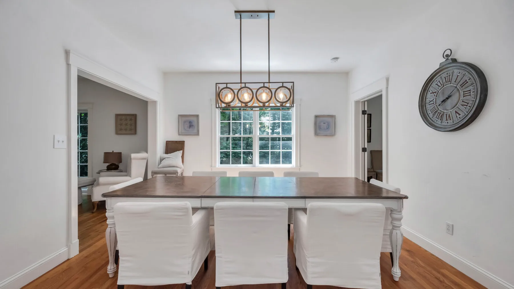 A bright dining room with a long table, upholstered seating, and large windows.