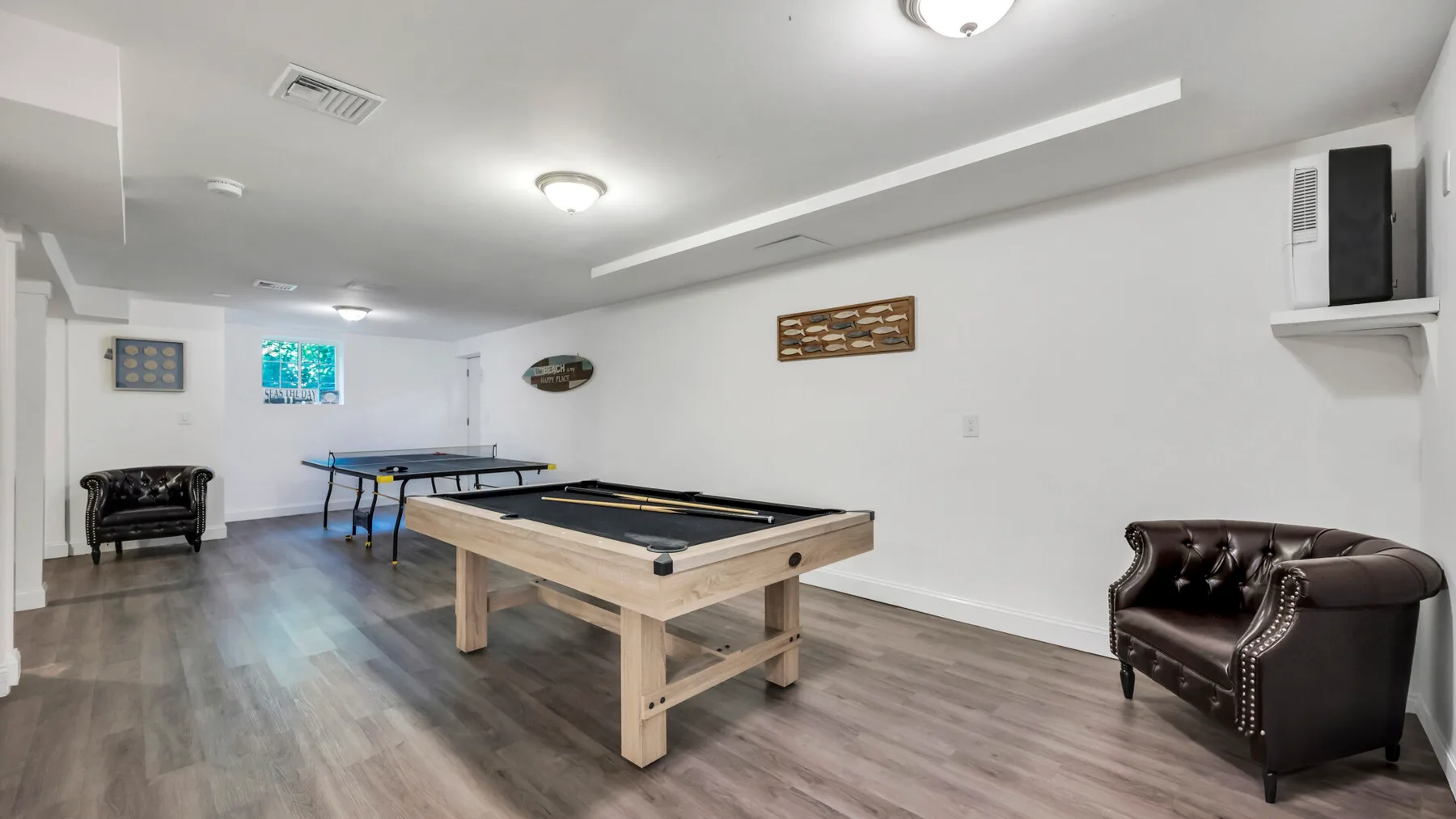A game room with a pool table and additional seating.