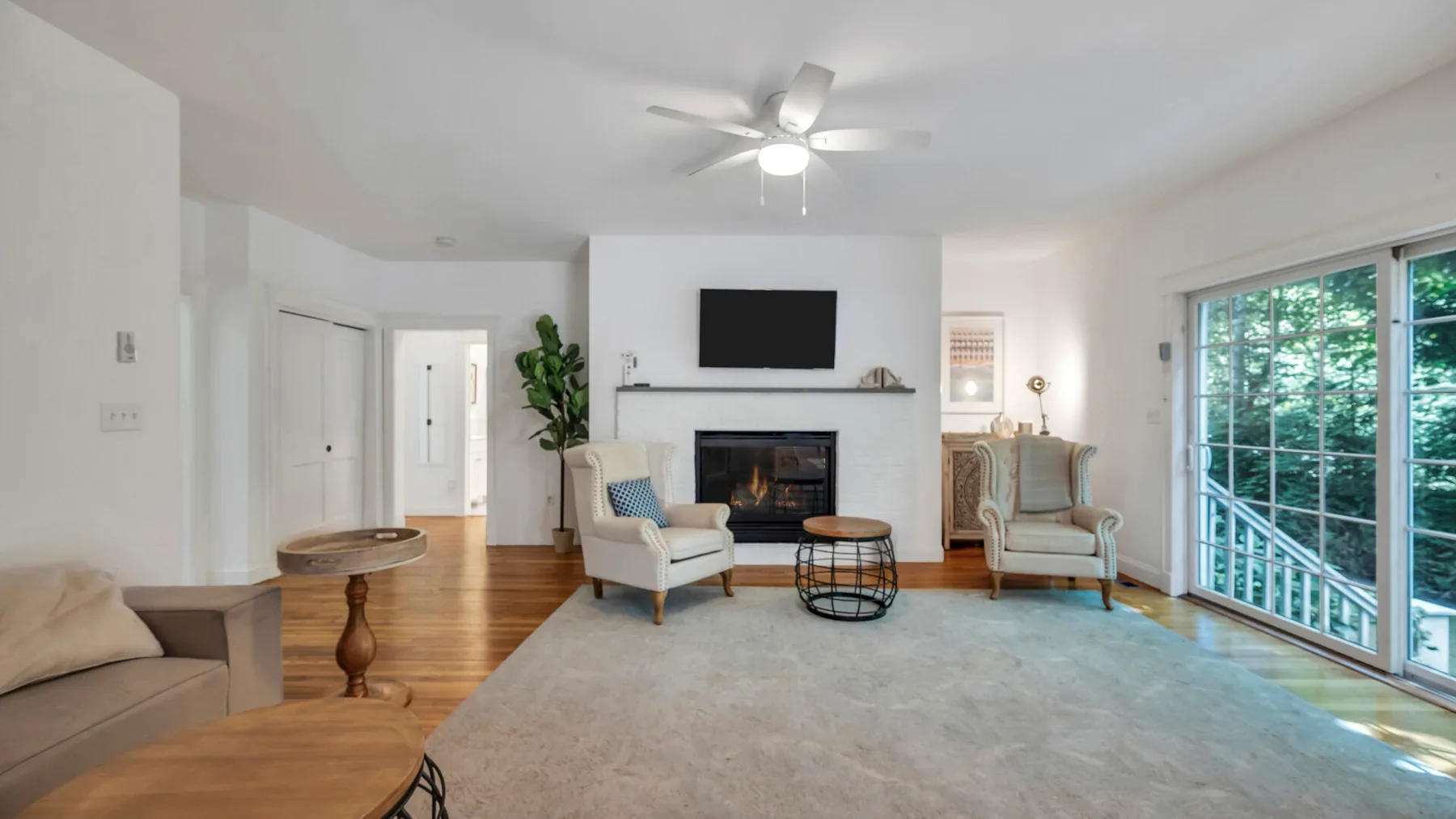 A bright living room with a fireplace, seating, and large windows.