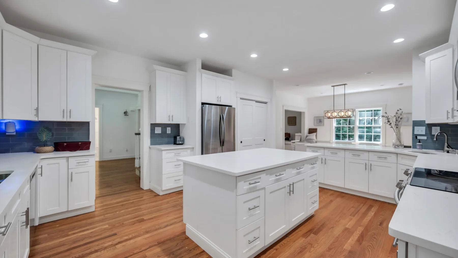 A bright kitchen with white cabinetry, a central island, and wood flooring.