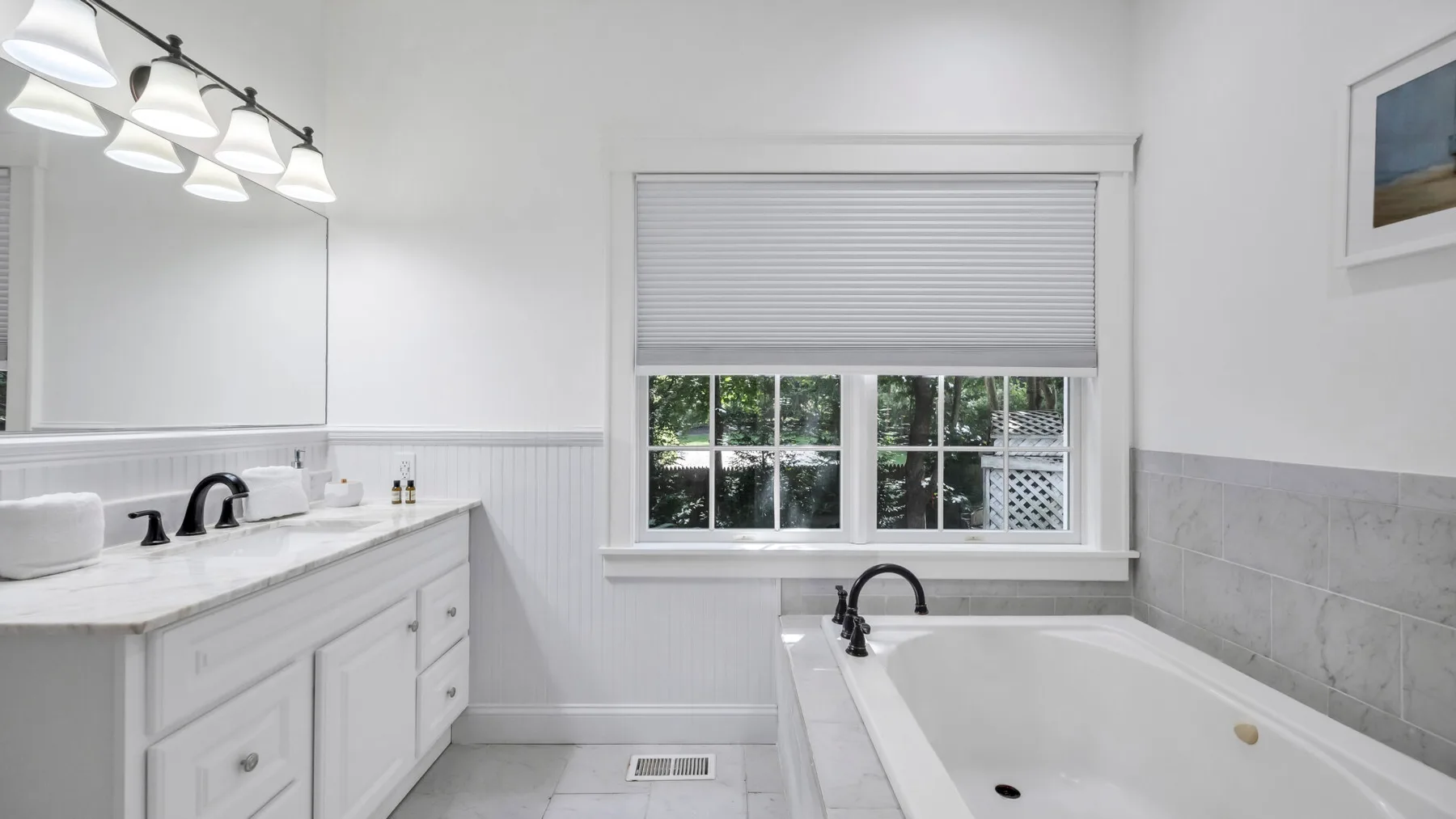 A bright bathroom with a bathtub, vanity, and window.