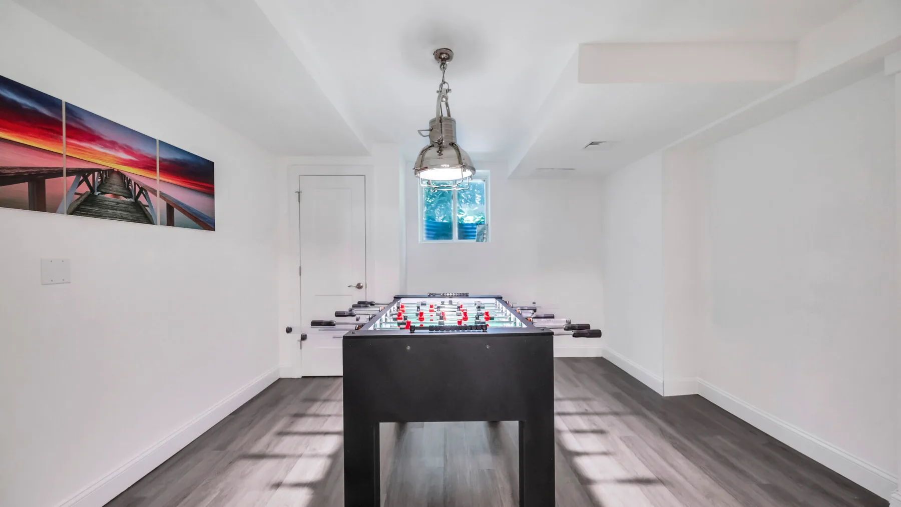 A bright game room with a foosball table and wall art.