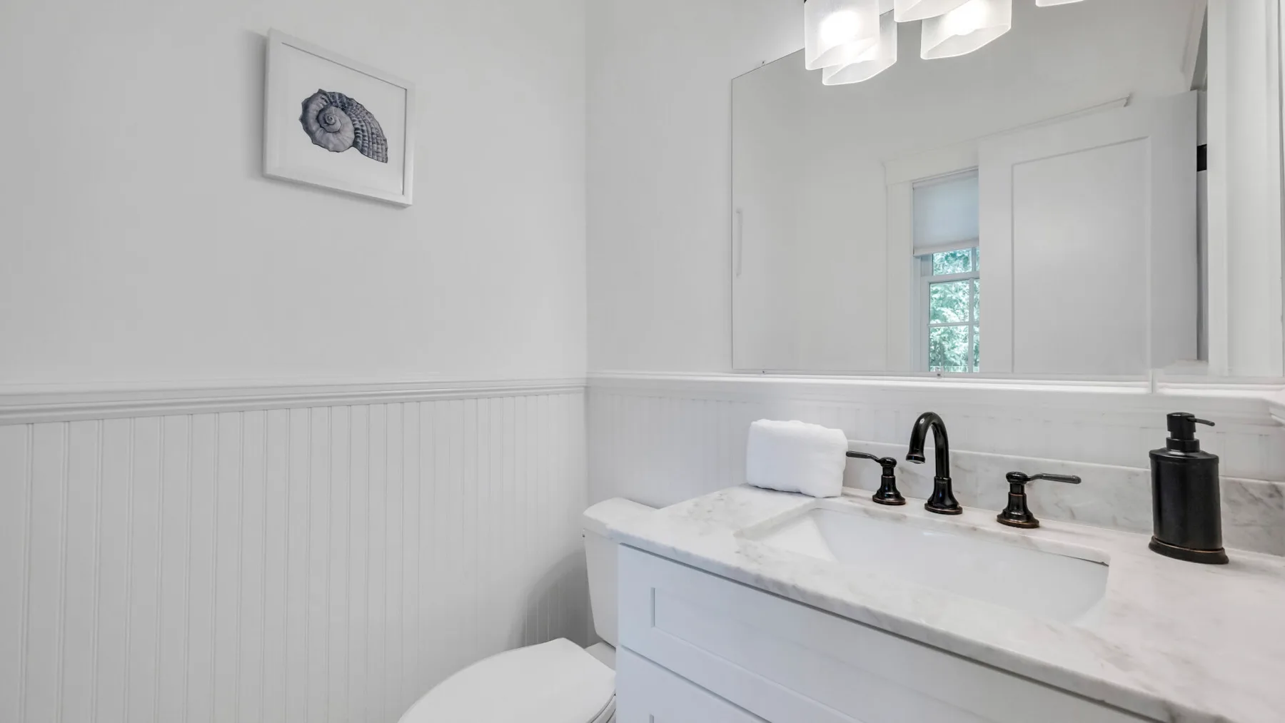 A bright bathroom with a white vanity, sink, and large wall mirror.