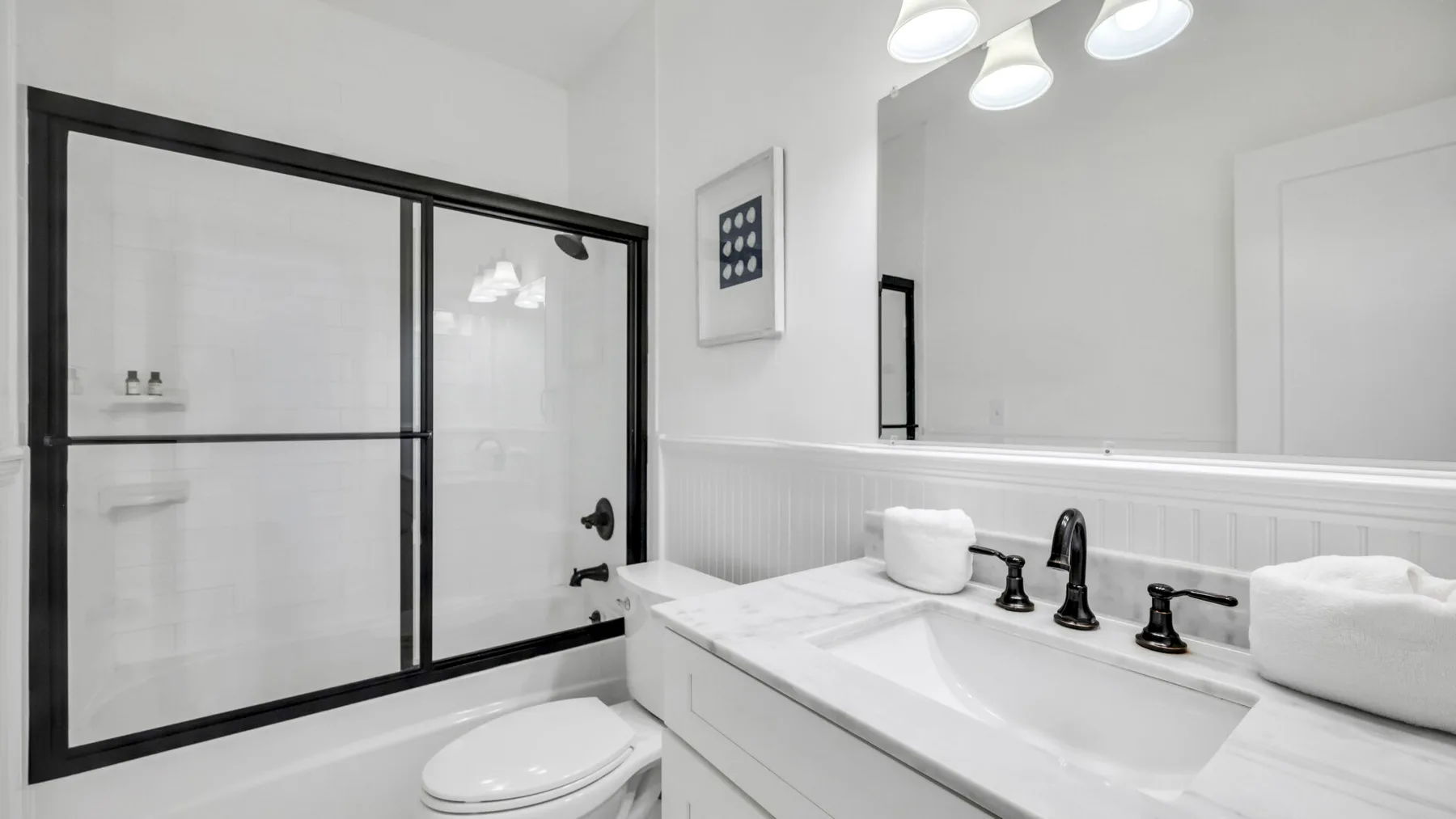 A bright bathroom with a wide vanity and a large black-framed mirror.