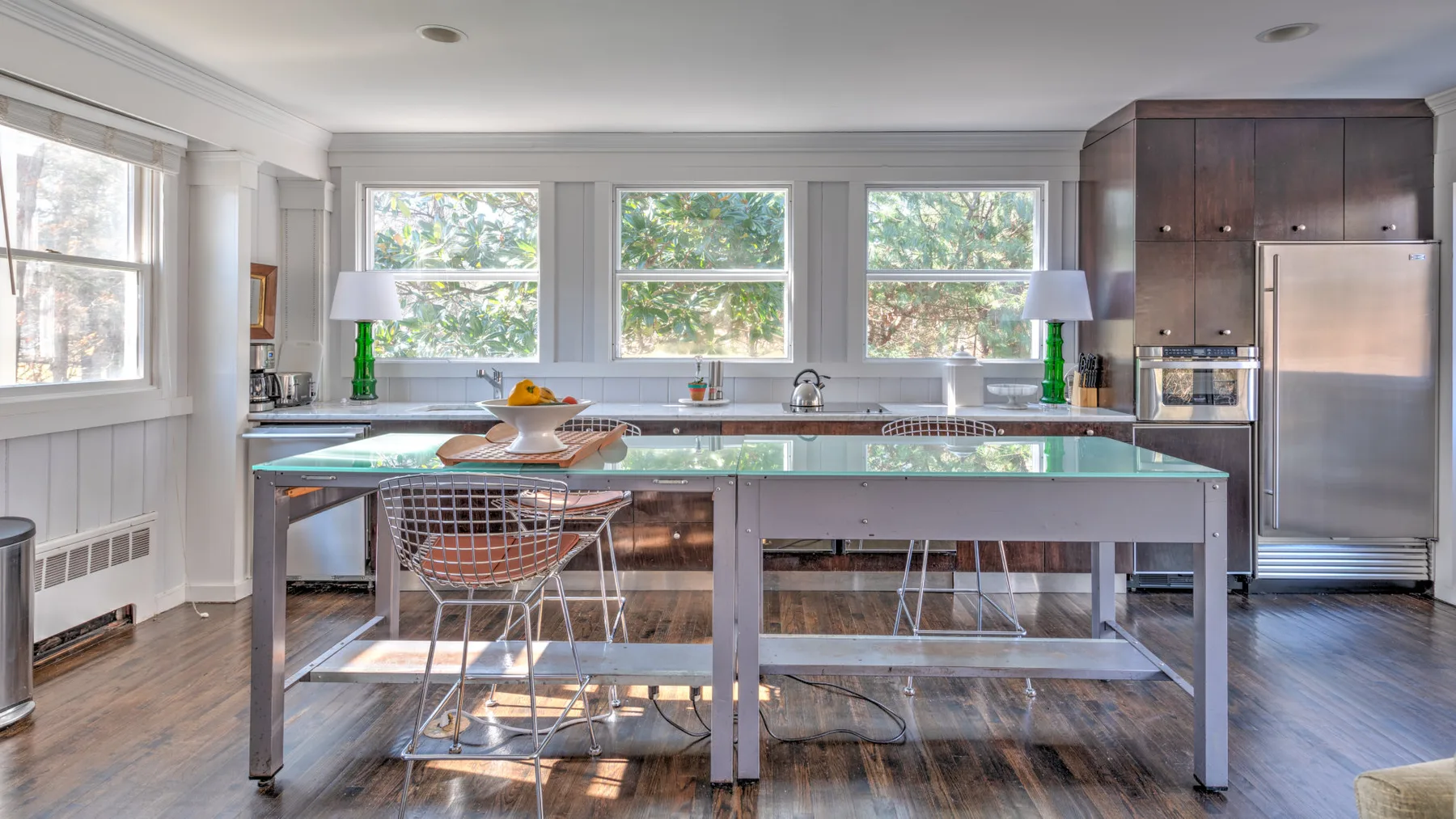 Una cocina luminosa con una isla grande, electrodomésticos de acero inoxidable y ventanas.