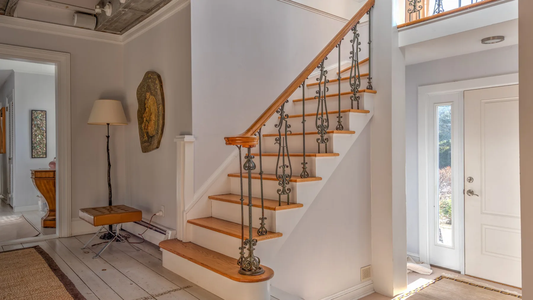 Un recibidor interior con una escalera y una barandilla decorativa de metal.