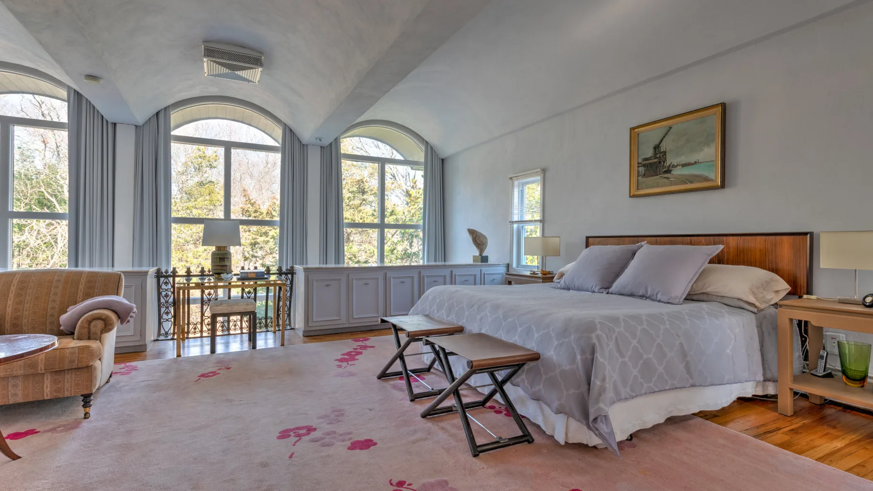 Un dormitorio luminoso con una cama grande y altas ventanas arqueadas.