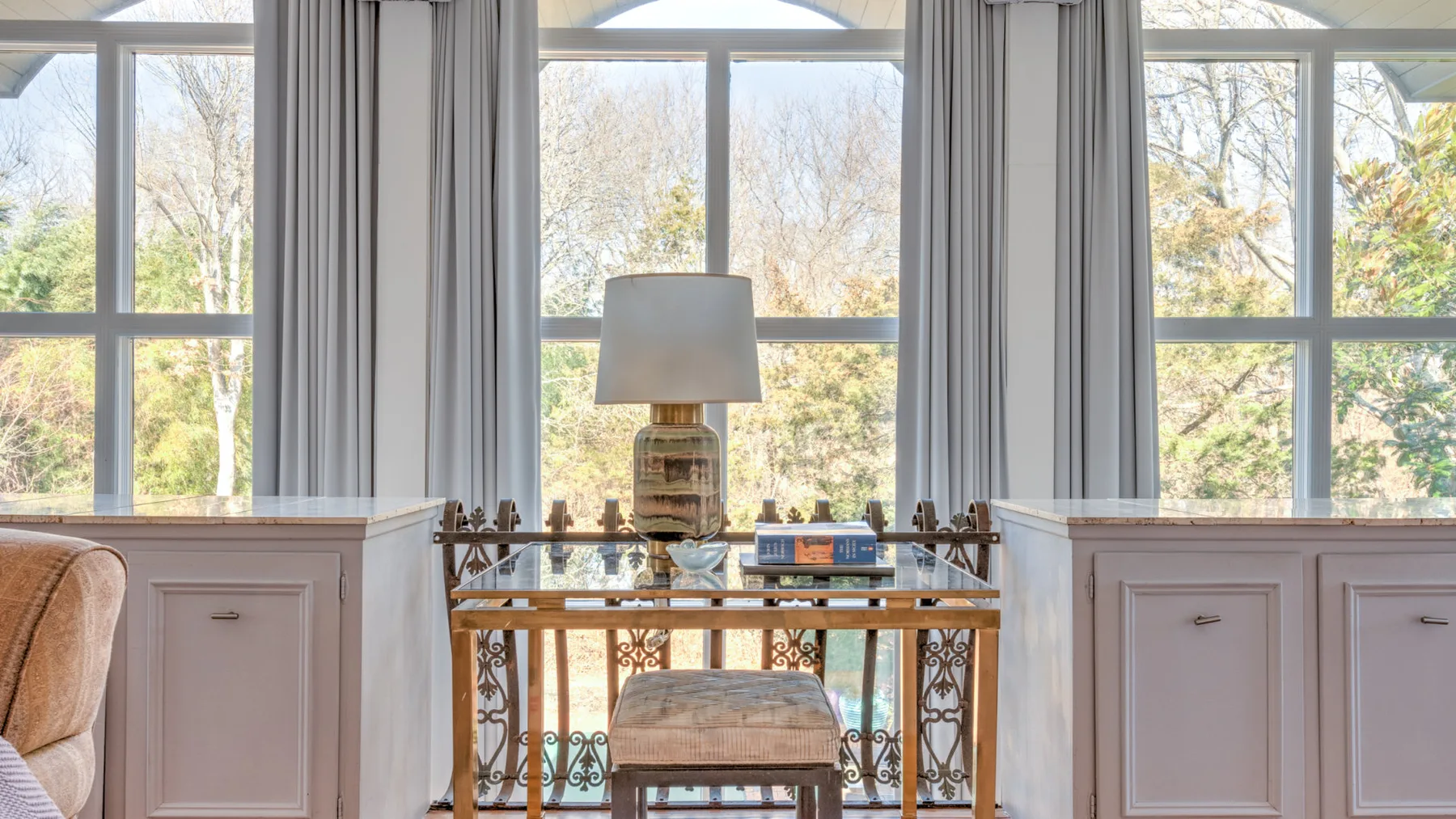 Una sala luminosa con grandes ventanas, una mesa y una lámpara.