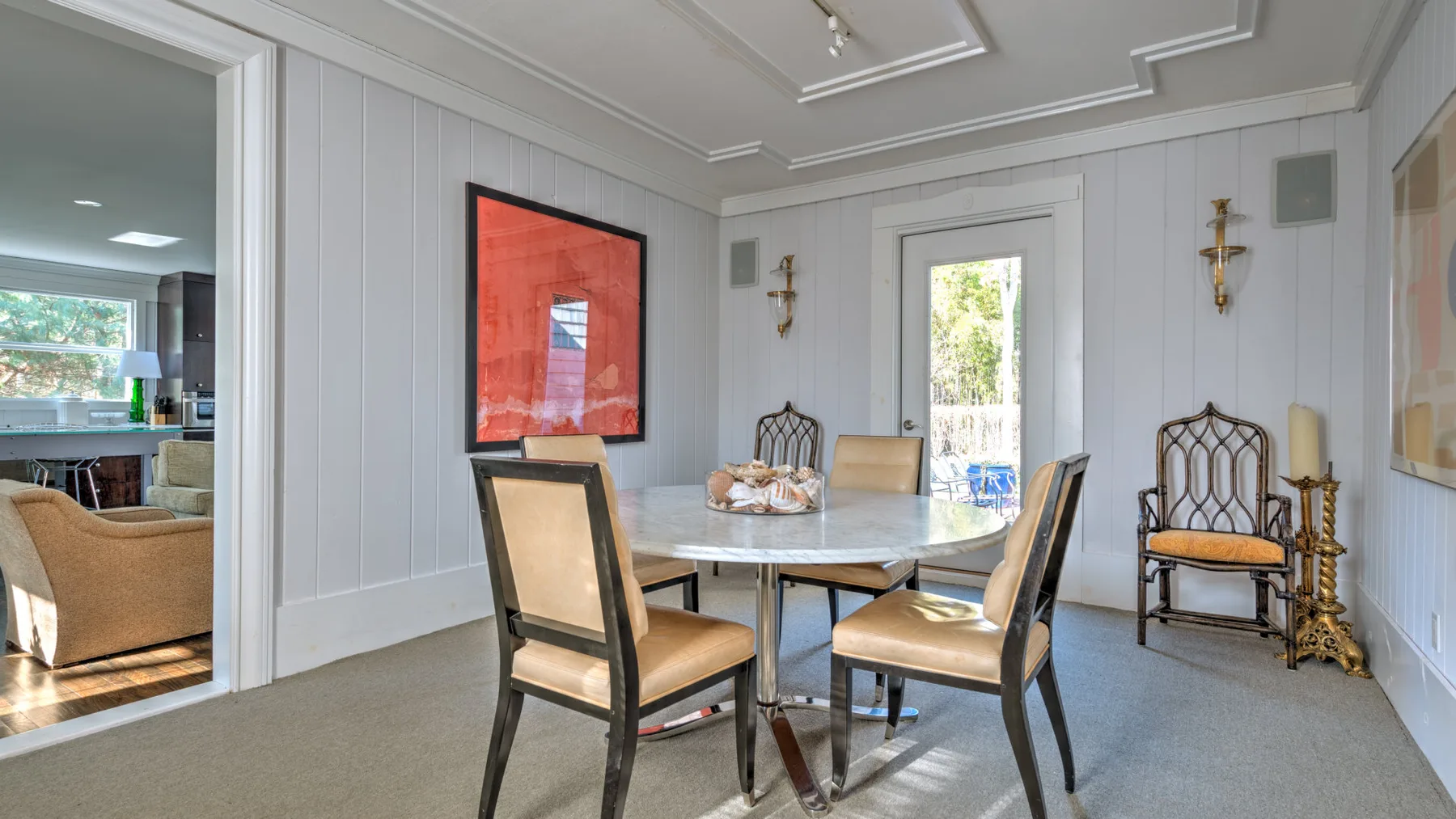 Un comedor con una mesa y sillas junto a una puerta con paneles de vidrio.