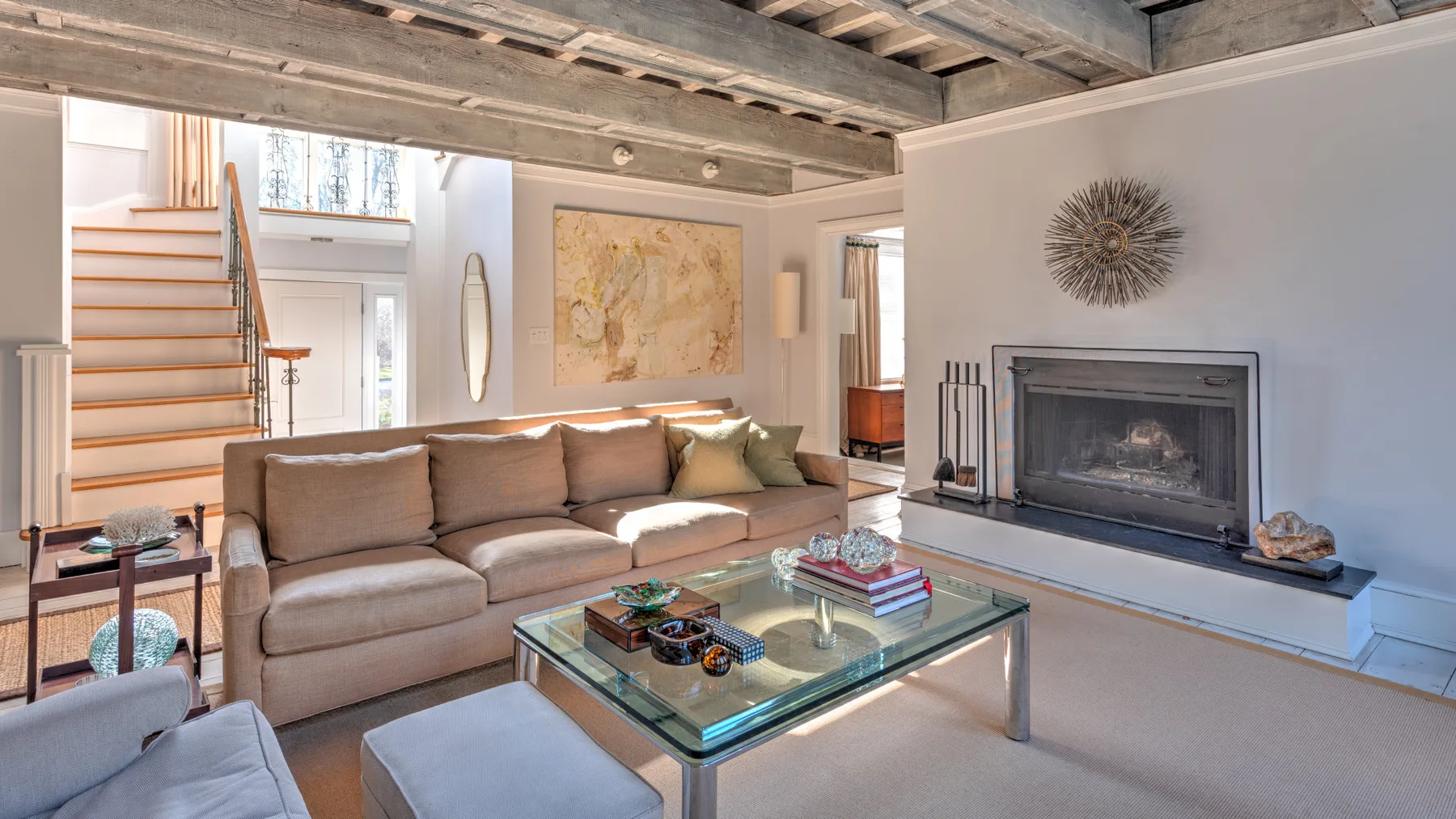 Una sala de estar con sofá seccional, mesa de centro de vidrio y chimenea.