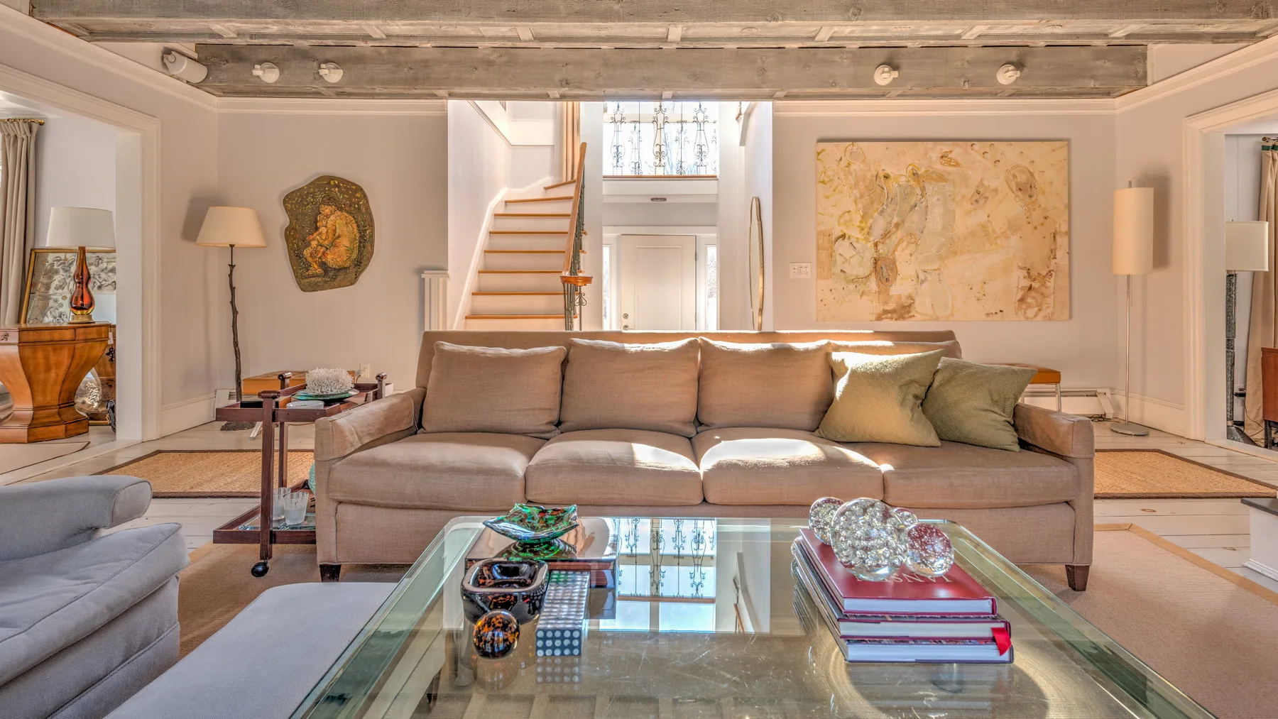 Una sala de estar con sofá, mesa de centro de vidrio y obras de arte.