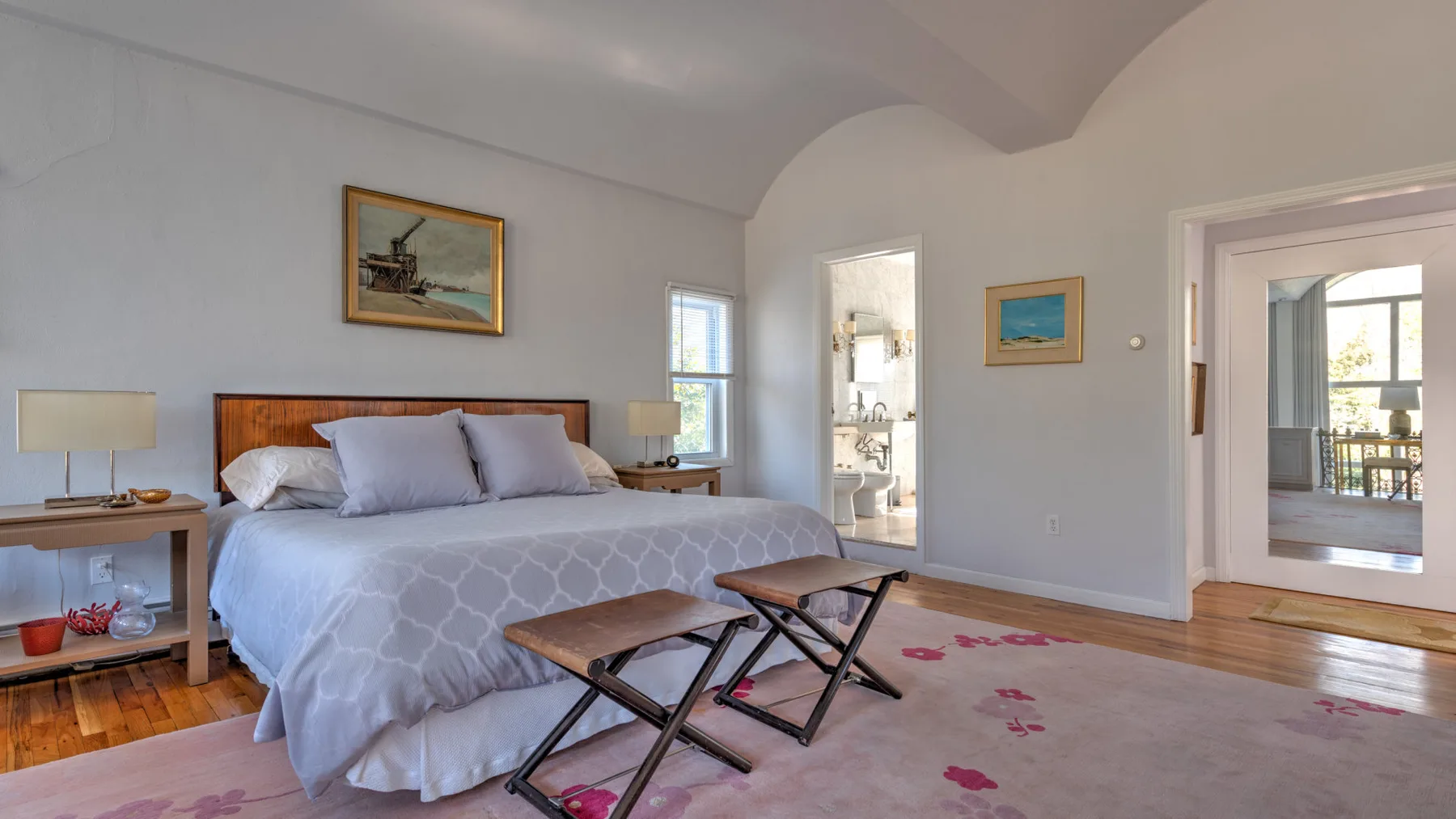 Un dormitorio con una cama, dos mesitas y una alfombra estampada.