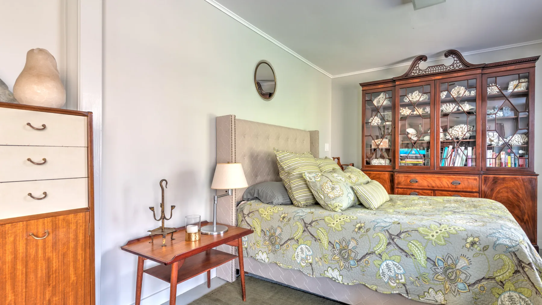 Un dormitorio con una cama junto a un mueble de madera con vitrinas.