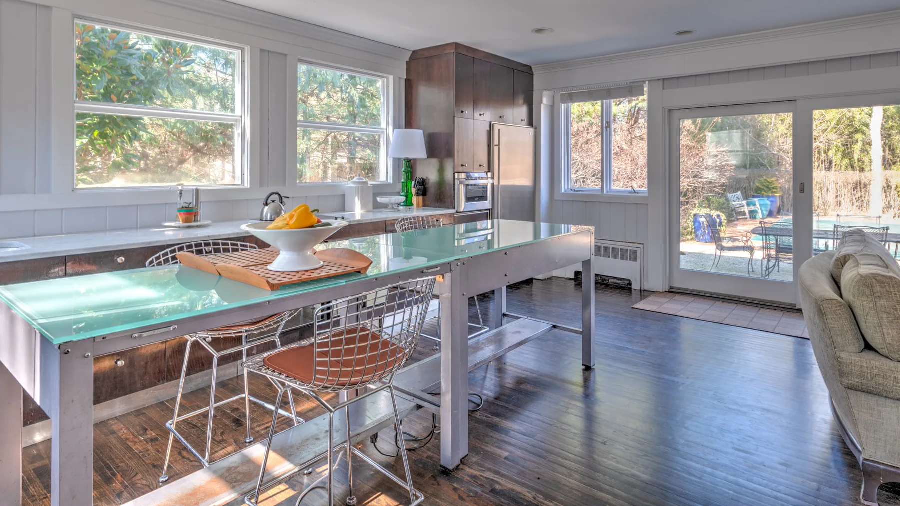 Una cocina luminosa con una isla y asientos junto a grandes ventanas.