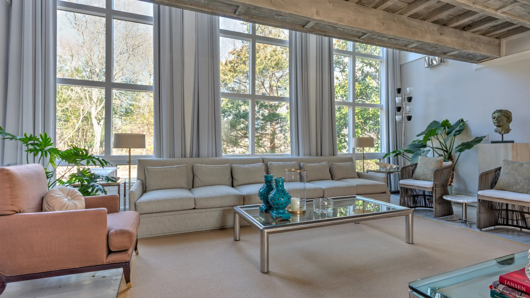 Una sala luminosa con grandes ventanas y asientos alrededor de una mesa de centro de vidrio.