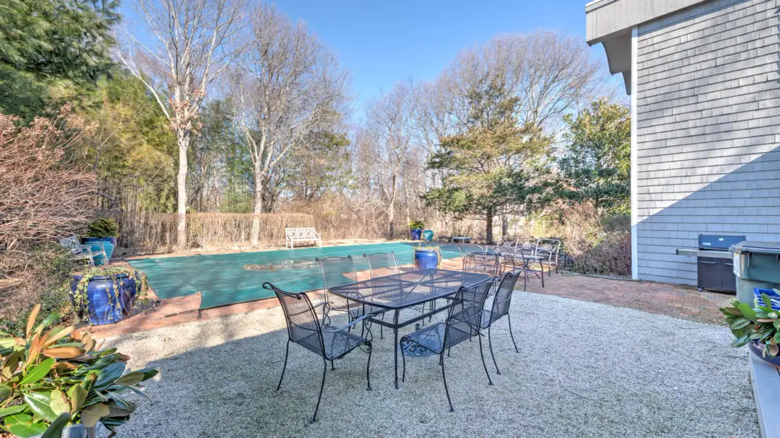 Un patio exterior con una mesa de comedor y sillas junto a una piscina.