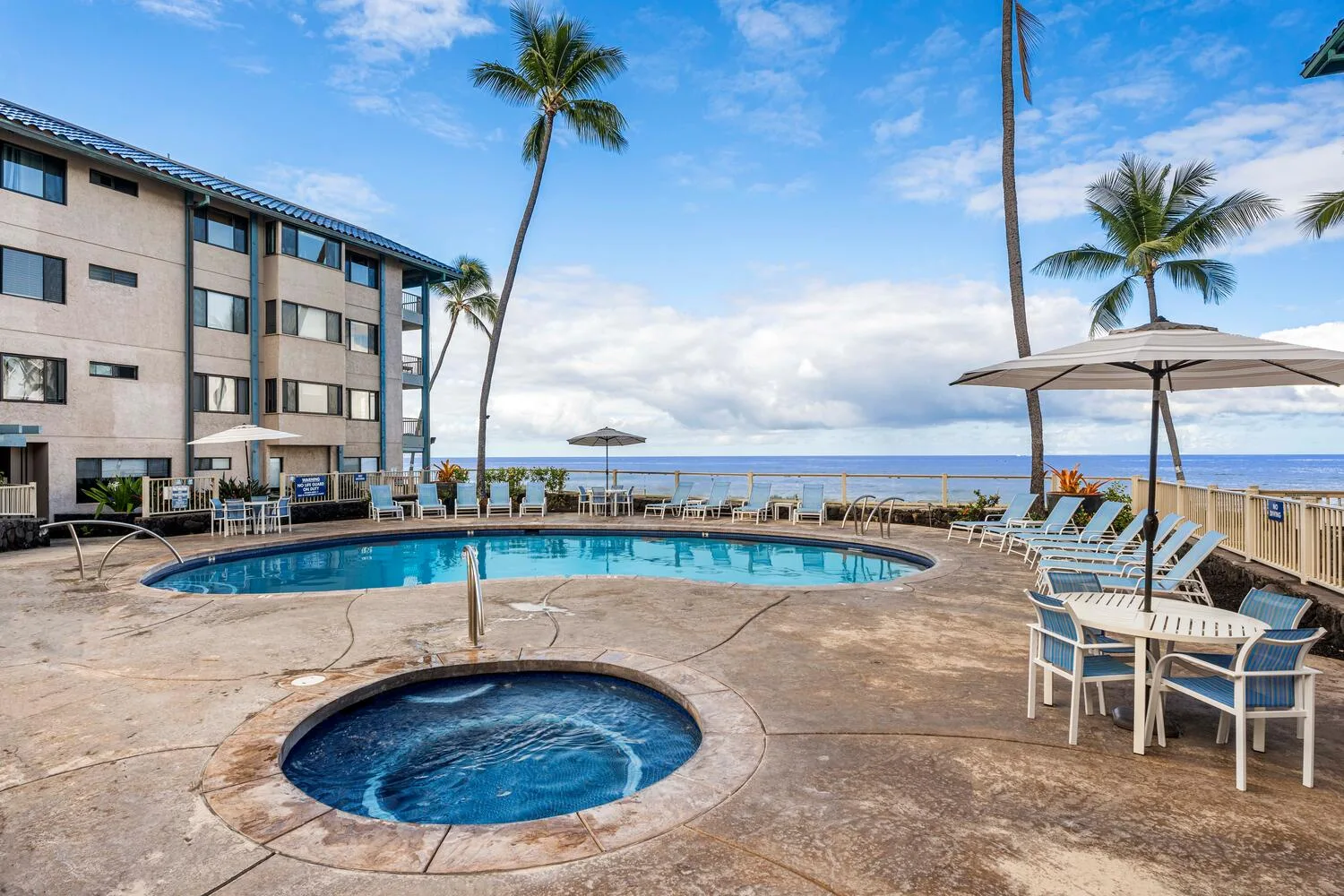 Una terraza junto al mar con piscina, jacuzzi circular y asientos.